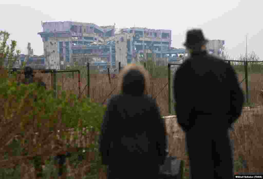 Un cuplu privește ruinele aeroportului în aprilie 2017. După ce Kremlinul a lansat invazia totală asupra Ucrainei în februarie 2022, întregul teritoriu al aeroportului distrus a fost preluat de forțele ruse, până în noiembrie a aceluiași an.