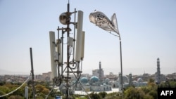 A Taliban flag flutters near telecom equipment installed over a rooftop providing Internet services overlooking Hazrat-e-Ali Shrine, or Blue Mosque, in Mazar-i-Sharif.