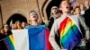 Жыныстық азшылық туын ұстаған адамдар қарсылық акциясында Ресей гимнін айтып тұр. Стокгольм, 6 қазан 2013 жыл.