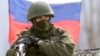Украинадағы Ресей әскери базасы маңында тұрған, айырым белгісі жоқ киім киген адам. Симферополь, 14 наурыз 2014 жыл.