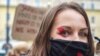 Žena na protestima u Varšavi nosi masku s usvojenim simbolom crvene munje (28. oktobar 2020.)